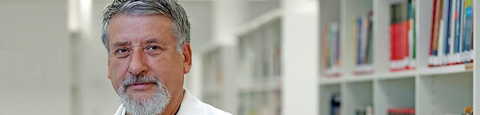 Kütüphande bir raftan kitap alan gülümseyen bir adamın portresi 